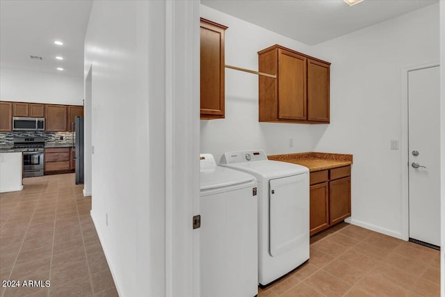 clothes washing area with cabinets, washing machine and dryer, and light tile patterned flooring