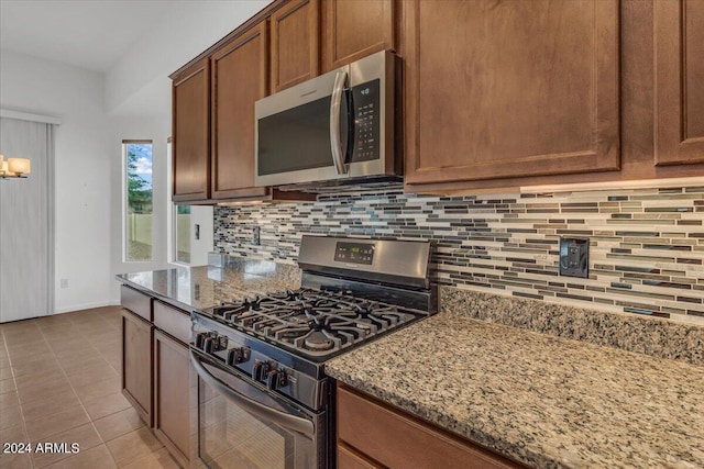 kitchen featuring decorative backsplash, light tile patterned flooring, appliances with stainless steel finishes, and stone counters