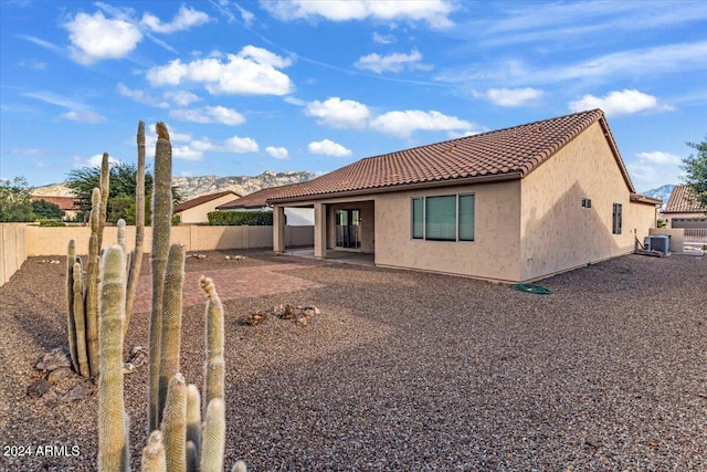 rear view of property with central air condition unit, a mountain view, and a patio area