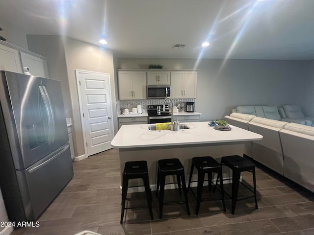 kitchen with a kitchen island with sink, appliances with stainless steel finishes, a breakfast bar area, and sink