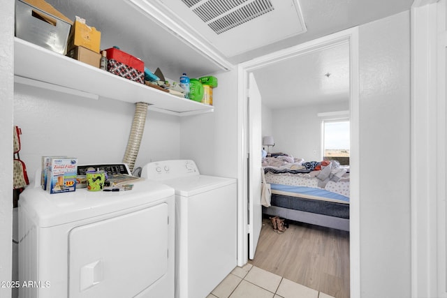 laundry area with washer and clothes dryer, visible vents, laundry area, and light tile patterned floors