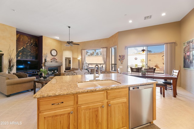 kitchen featuring a ceiling fan, a fireplace, a sink, stainless steel dishwasher, and open floor plan