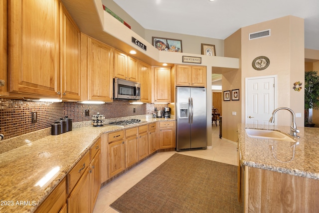 kitchen with backsplash, light stone counters, appliances with stainless steel finishes, light tile patterned flooring, and a sink