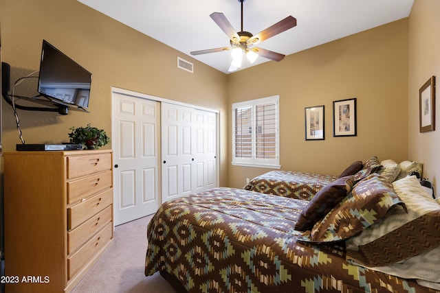 bedroom with light carpet, visible vents, a ceiling fan, and a closet