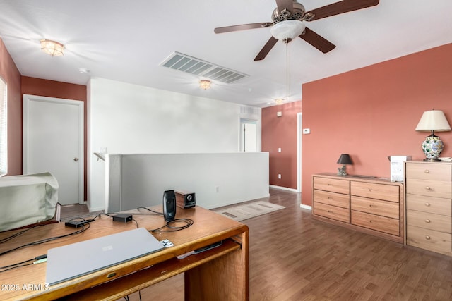 home office featuring ceiling fan, wood finished floors, visible vents, and baseboards