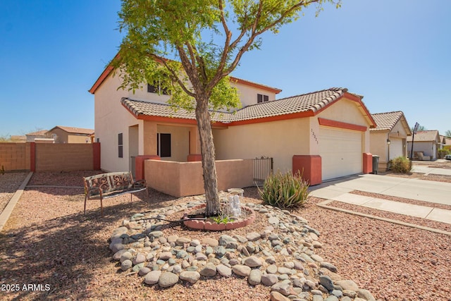 mediterranean / spanish house featuring a garage, concrete driveway, fence, and stucco siding