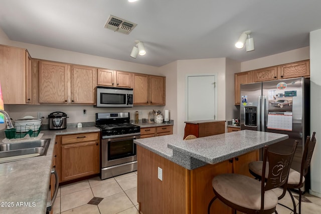 kitchen featuring visible vents, a kitchen island, a breakfast bar area, stainless steel appliances, and a sink