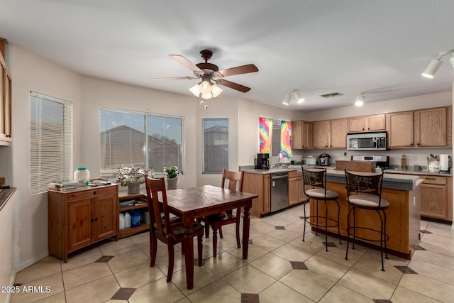 kitchen featuring visible vents, ceiling fan, a breakfast bar, a center island, and stainless steel appliances