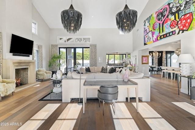 living room with an inviting chandelier, hardwood / wood-style floors, and a towering ceiling