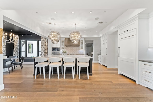 kitchen featuring a spacious island, white cabinetry, a breakfast bar, and paneled built in refrigerator