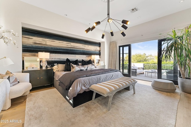 bedroom featuring a notable chandelier, access to exterior, and light wood-type flooring