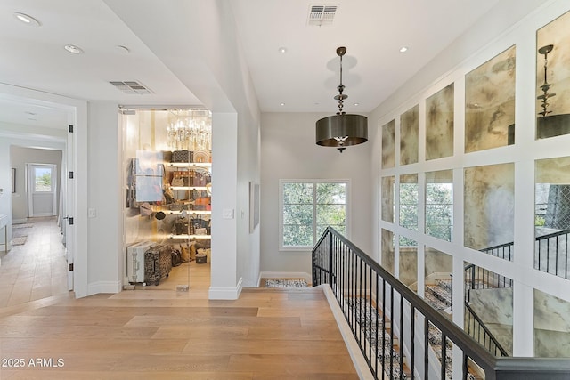 corridor with a towering ceiling, plenty of natural light, and light hardwood / wood-style floors