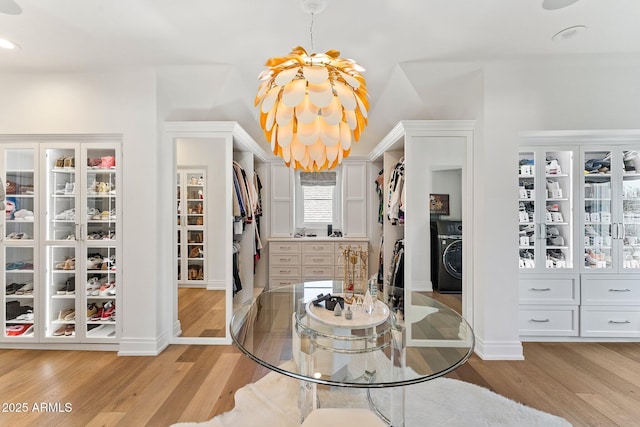 dining space featuring washer / dryer, a chandelier, and light wood-type flooring