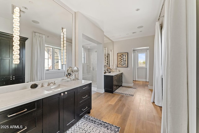 bathroom with wood-type flooring, a shower, a wealth of natural light, and vanity