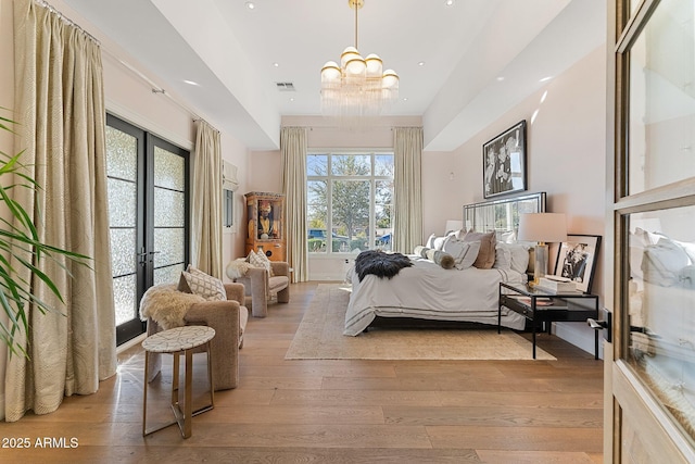 bedroom with french doors, a chandelier, and light wood-type flooring