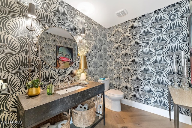 bathroom with wood-type flooring, toilet, and sink