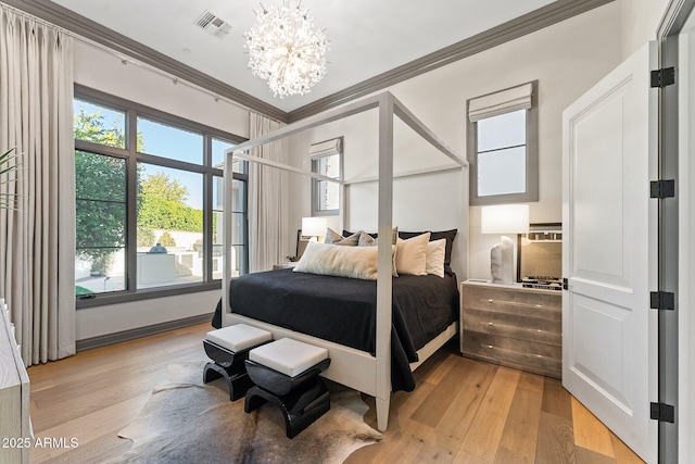 bedroom with crown molding, a chandelier, and light hardwood / wood-style flooring