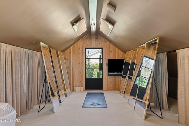 interior space featuring light colored carpet, wooden walls, vaulted ceiling, and a wealth of natural light