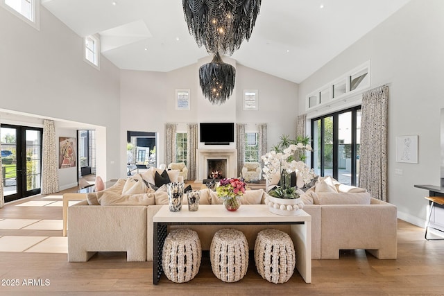 living room with high vaulted ceiling, light hardwood / wood-style flooring, a chandelier, and french doors