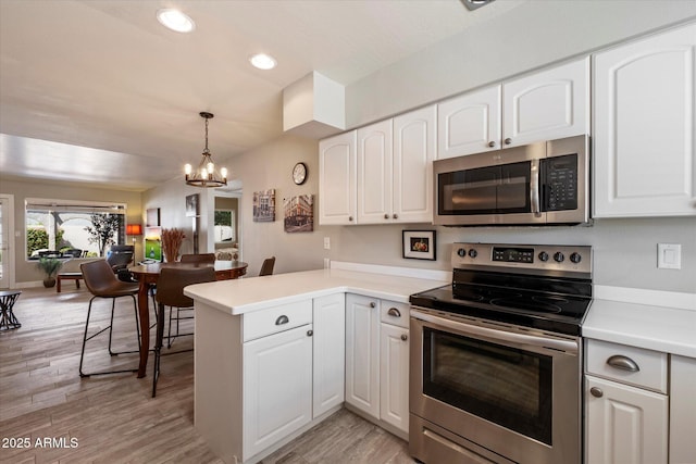 7736 E Hazelwood St, Scottsdale, AZ 85251 - kitchen with a peninsula, light wood-style floors, white cabinets, a notable chandelier, and stainless steel appliances