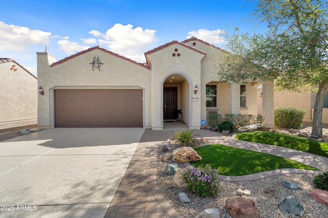 mediterranean / spanish house with a garage, concrete driveway, a tiled roof, and stucco siding