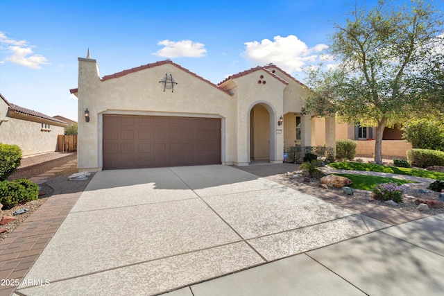 mediterranean / spanish home with concrete driveway, a tile roof, an attached garage, and stucco siding