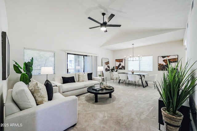 living room with ceiling fan with notable chandelier, light colored carpet, vaulted ceiling, and a wealth of natural light