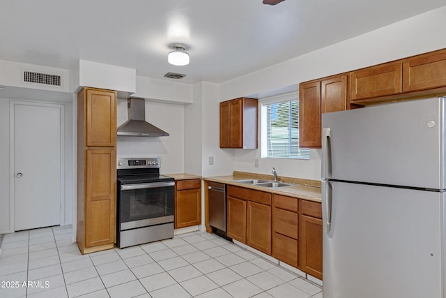 kitchen with visible vents, a sink, stainless steel appliances, light countertops, and wall chimney exhaust hood