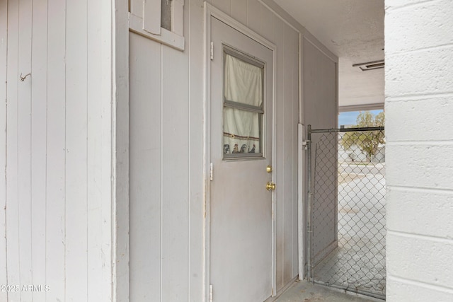 view of exterior entry with brick siding and a gate