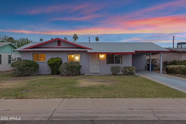 ranch-style home featuring a carport, concrete driveway, a lawn, and a shingled roof