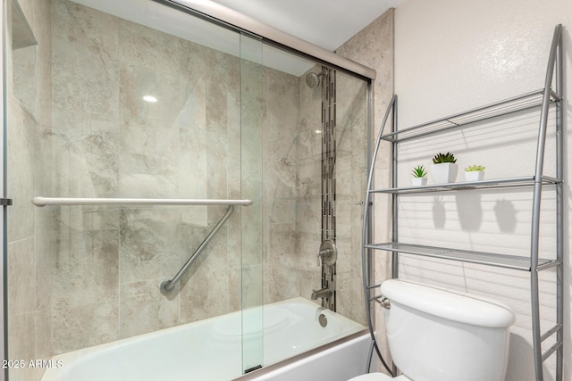 bathroom featuring bath / shower combo with glass door and toilet
