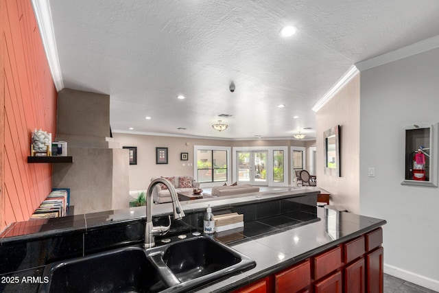 kitchen with a sink, dark countertops, ornamental molding, open floor plan, and recessed lighting