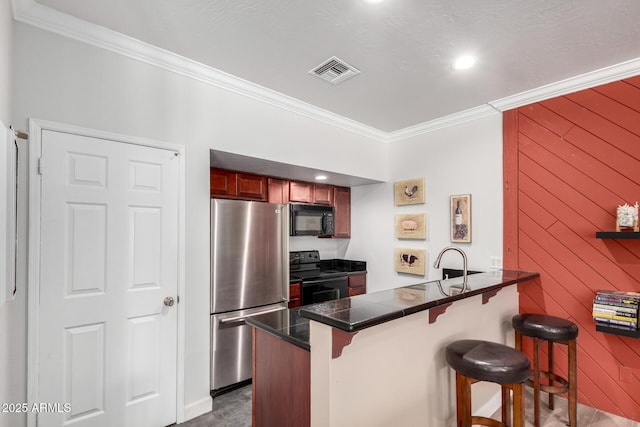 kitchen featuring black appliances, crown molding, a peninsula, a kitchen breakfast bar, and tile counters