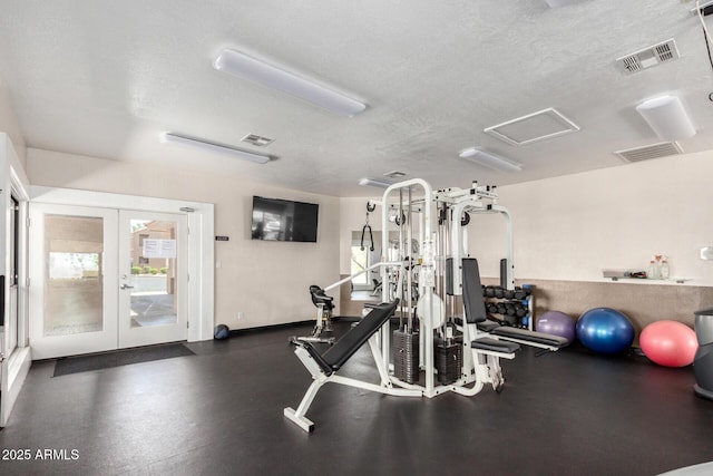 exercise room with french doors, a textured ceiling, and attic access