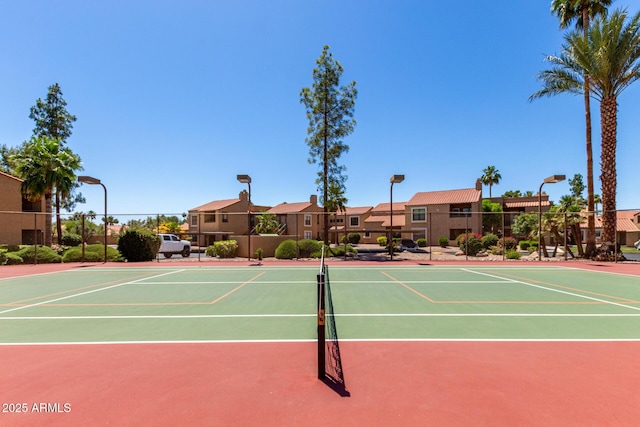 view of tennis court featuring community basketball court, fence, and a residential view