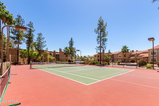 view of tennis court featuring community basketball court, fence, and a residential view