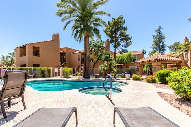 community pool featuring a community hot tub, fence, a patio area, and a residential view