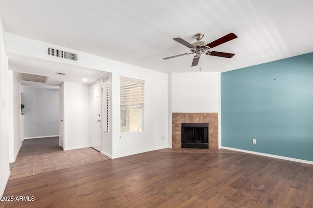 unfurnished living room with ceiling fan, wood finished floors, baseboards, and a fireplace