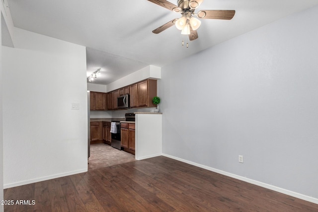 kitchen with appliances with stainless steel finishes, dark wood-type flooring, ceiling fan, and baseboards