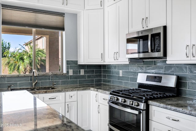 kitchen with a sink, decorative backsplash, stainless steel appliances, and white cabinetry