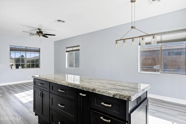 kitchen with dark cabinetry, baseboards, ceiling fan, and visible vents