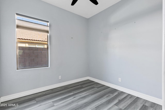 spare room with baseboards, a ceiling fan, and wood finished floors