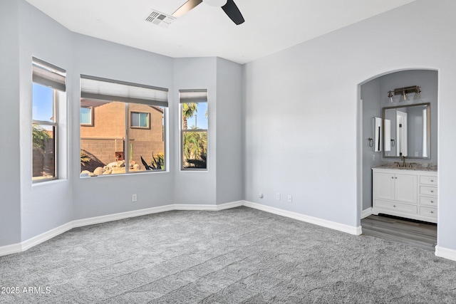 unfurnished bedroom featuring visible vents, baseboards, a sink, carpet, and ensuite bath