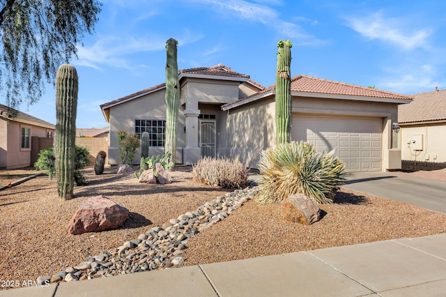 view of front of property featuring a tile roof, an attached garage, driveway, and stucco siding