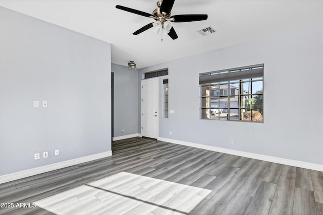 unfurnished room with baseboards, ceiling fan, wood finished floors, and visible vents