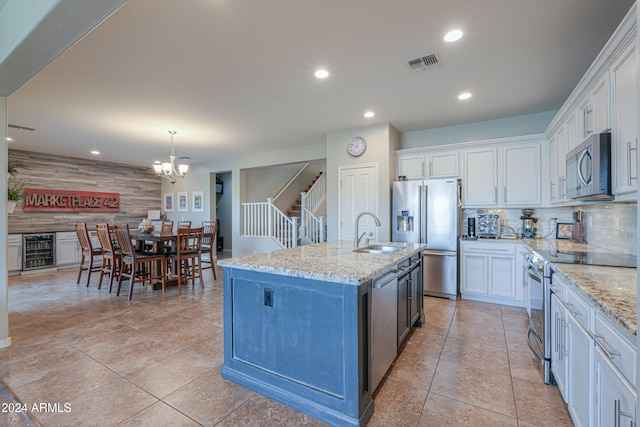 kitchen featuring white cabinetry, sink, beverage cooler, stainless steel appliances, and a center island with sink