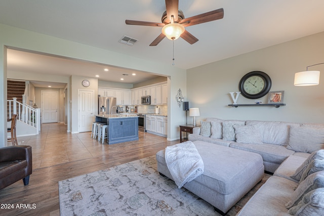 living room featuring ceiling fan, light hardwood / wood-style floors, and sink