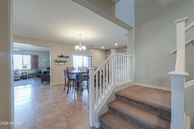 stairs featuring tile patterned floors, plenty of natural light, and a notable chandelier