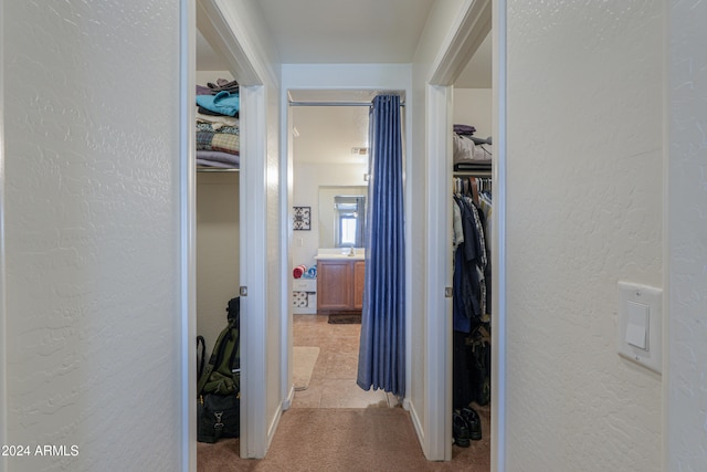 hall with light colored carpet and sink