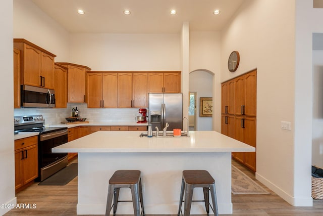 1635 E Harrison St, Chandler, AZ 85225 - kitchen featuring stainless steel appliances, an island with sink, a breakfast bar, light wood-style flooring, and backsplash